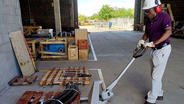 person with hardhat moving items with a forklift