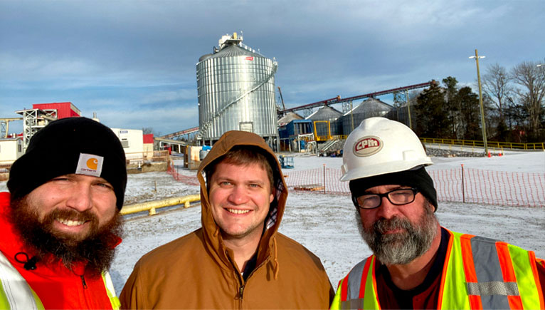 three workers outside with hats on