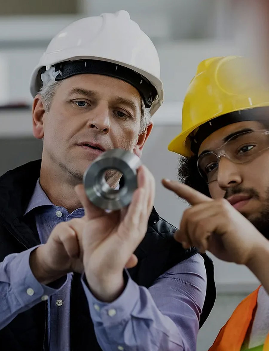 two men with hardhats looking at a metal ring