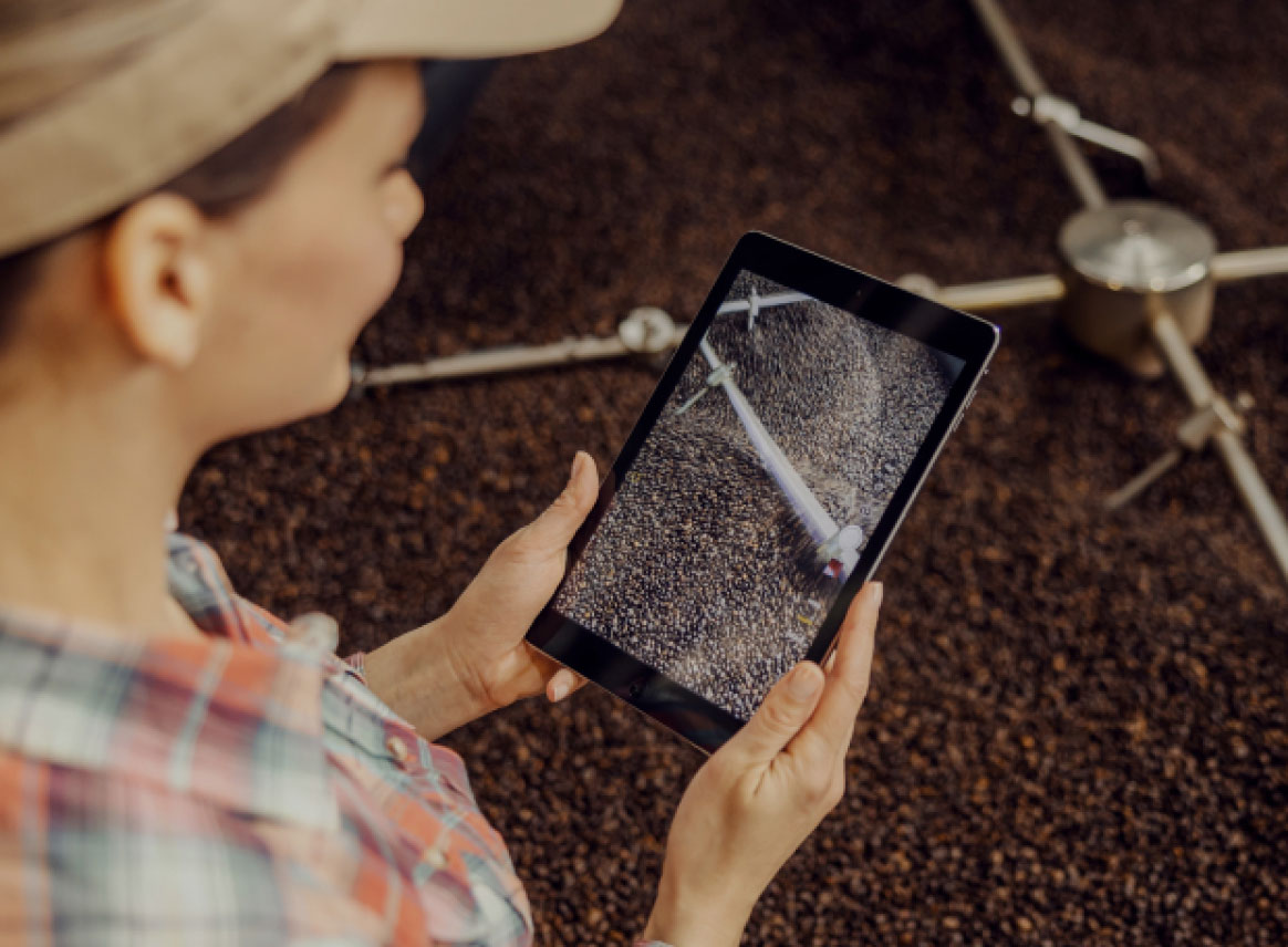 person taking a photo on their tablet of beans processing