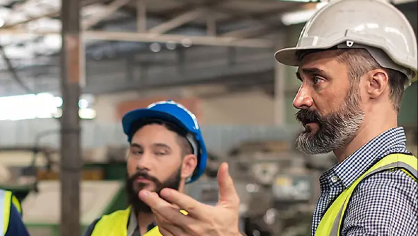 two men with hard hats talking in warehouse