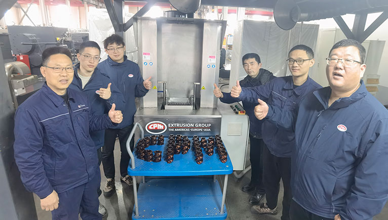 a group of 6 men in navy blue jumpsuits in machinery room with their thumbs up