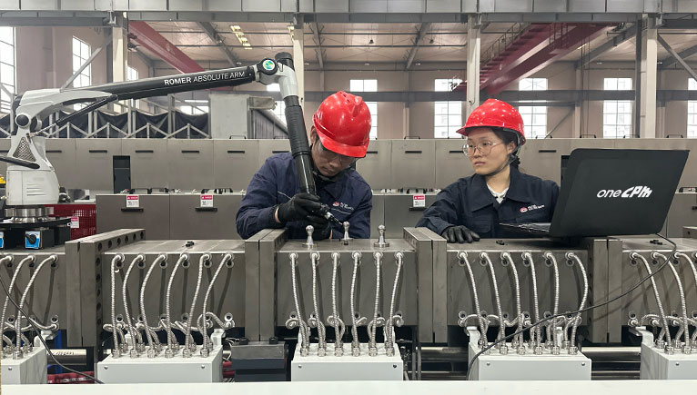 Two people with hardhats, working on machinery