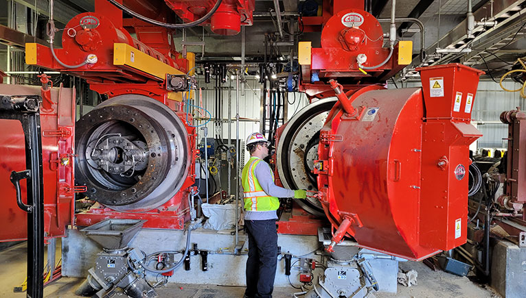 man with hard hat inspecting bright red machinery